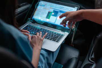 Auto technician working in repair workshop, examining ECU engine system with laptop and OBD2 wireless scanning tool, car information displayed on screen interface