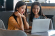 © StockPhotoRepublic - Weekend Out-of-Office Collaboration. Two young Asian woman break away from the office, opting for a cozy café to discuss work.