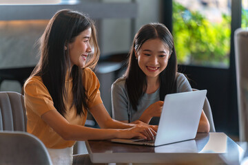 Weekend Out-of-Office Collaboration. Two young Asian woman break away from the office, opting for a cozy café to discuss work. 