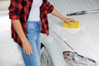 Woman in red shirt cleaning the car at car wash
