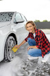 Woman in red shirt washing the car wheels