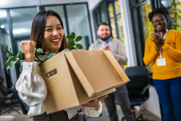 Business team meets a new employee.  New coworker holding a box standing in the modern office with other colleagues