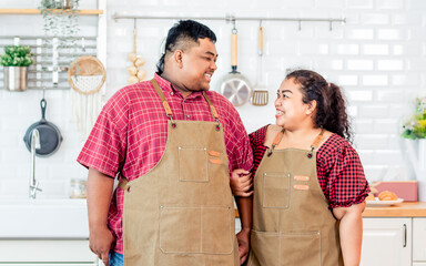 Wall Mural - Portrait Asian two people of couple, husband and wife standing, cooking in kitchen at cozy home, sweet looking each other, smiling with happiness, love. Relationship, Family Concept.