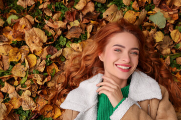 Wall Mural - Smiling woman lying among autumn leaves outdoors, top view. Space for text