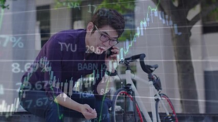 Wall Mural - Animation of financial data processing and graph over asian man talking on smartphone in city street