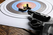 Shooting target, handgun and bullets on wooden table, closeup