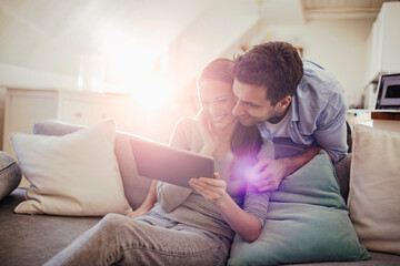 Happy young couple using table on sofa at home