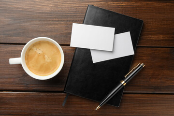 Poster - Blank business cards, coffee and notebook on wooden table, flat lay. Mockup for design