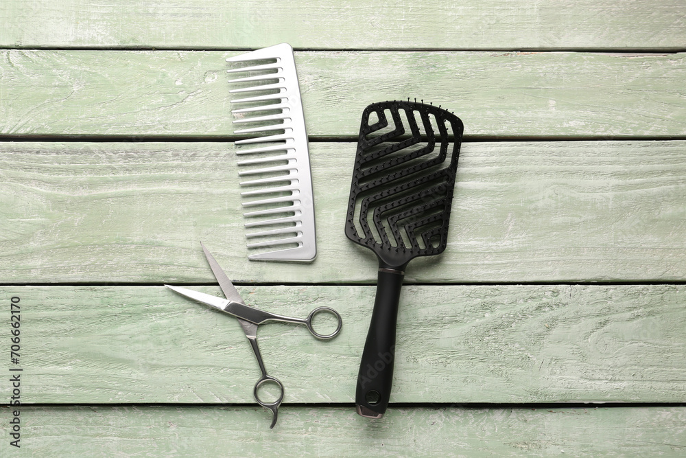 Hair brushes with scissors on green wooden background