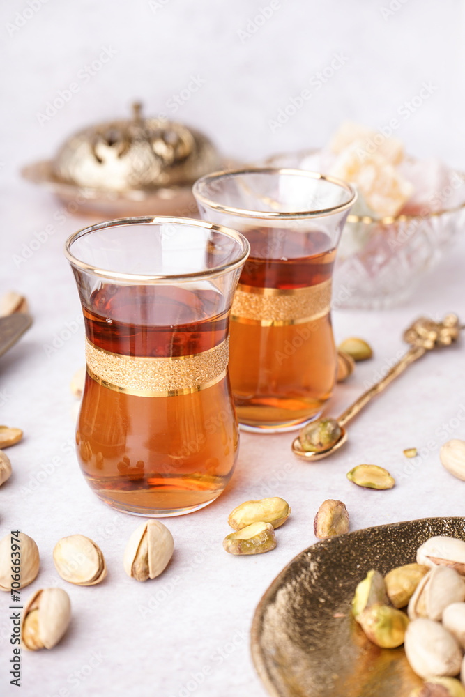 Glasses of Turkish tea and pistachios on white background