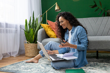 Young beautiful woman sitting on the floor at home in the living room, student studying remotely, using laptop to watch webinar and video course, online call consultation with teacher.