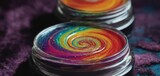 Fototapeta Tęcza -  a close up of a jar of paint with a colorful swirl design on the inside of the jar on a purple table cloth.