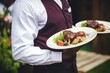 © Daniela - Waiter carrying plates with amazing meat dish. Catering service concept