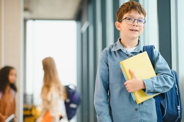 Wall Mural - Schoolboy with schoolbag and books in the school. Education concept. Back to school. Schoolkid going to class. Stylish boy with backpack. Boy ready to study