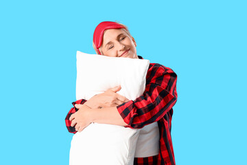 Poster - Mature woman in pajamas with pillow on blue background