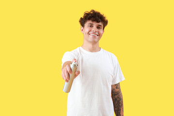 Canvas Print - Handsome young man with bottle of hair spray on yellow background