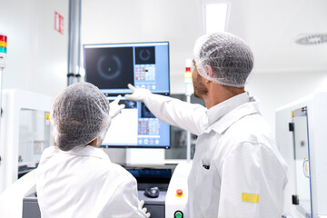 Wall Mural - Factory coworkers analyzing production and checking monitors at assembly line.