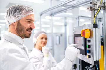 Wall Mural - Experienced worker showing trainee to operate modern automated machine in factory.