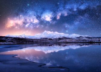 Wall Mural - Bright Milky Way over snowy mountains and sea coast at winter night. Landscape with snowy rocks, starry sky, reflection in water, fjord. Lofoten Islands, Norway. Space. Beautiful milky way and stars
