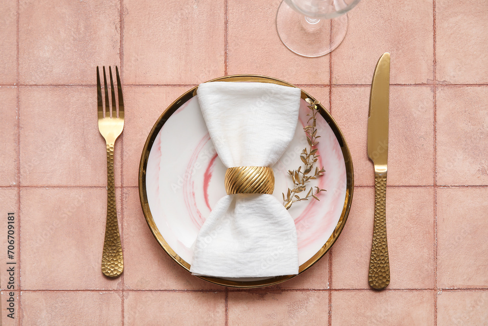 Elegant table setting with golden leaves and cutlery on beige tiled background