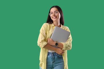 Pretty young female programmer with laptop on green background