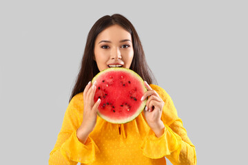 Poster - Beautiful young Asian woman with half of fresh watermelon on grey background