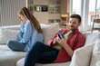 Woman crying turning out of man sitting on couch at home. Husband ignoring wife emotions looking at smartphone screen. Couple spouses misunderstanding in relationships, jealous mistrust concept. 