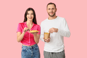 Wall Mural - Beautiful young couple with french fries on pink background