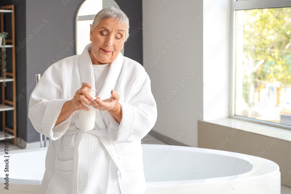 Senior woman applying cream in bathroom
