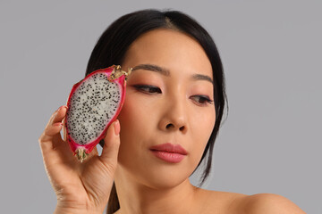 Sticker - Pretty young Asian woman with dragon fruit on grey background