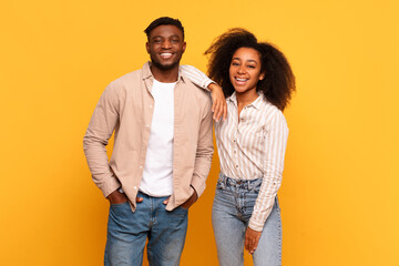 smiling black couple standing together against yellow background