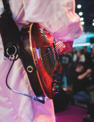 Wall Mural - Concert view of an electric guitar player with vocalist and rock band performing in a club, male musician guitarist on stage with audience in a crowded concert hall arena, hands on a guitar