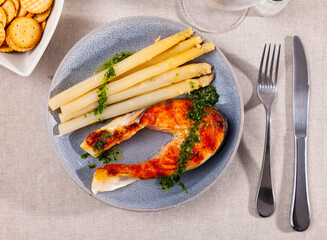 Wall Mural - Mediterranean cuisine, roasted sliced tasty salmon with asparagus on a table in a cafe