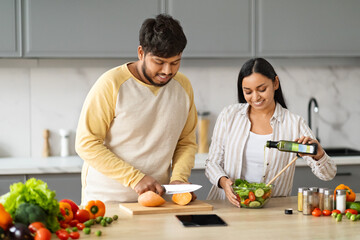 Wall Mural - Cute millennial eastern couple preparing healthy dinner together