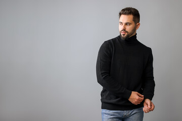 Canvas Print - Handsome man in stylish black sweater on grey background, space for text