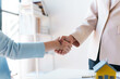 © amnaj - Real estate agent shakes hands with a client to sign a home purchase contract congratulating the client on the purchase.