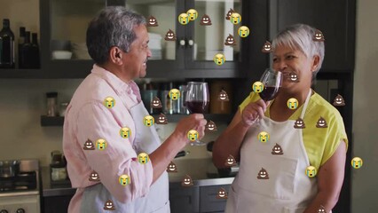 Sticker - Animation of emoji icons over senior biracial couple drinking wine in kitchen