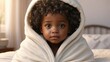 © noah - A heartwarming picture of a cute little African baby with curly hair, wrapped in a cozy white blanket on a bed. The baby has big beautiful eyes and a tiny nose, making it a perfect image for ads