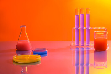 Wall Mural - Minimal background with lab concept. Test tubes, beaker, erlenmeyer flask and petri dishes filled with colorful solution on orange gradient background. Space for cosmetics and product presentation