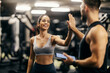 © Dusan Petkovic - A happy woman is giving high five to her fitness trainer in a gym.