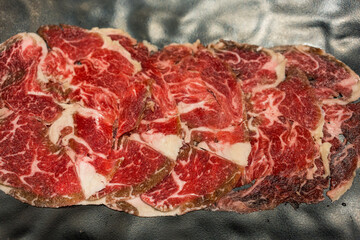 Wall Mural - Sliced fresh raw beef served on a black plate