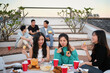 © Prathankarnpap - Diverse group of young people hanging out on a rooftop in the evening