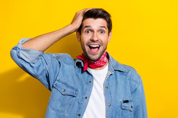 Wall Mural - Photo portrait of handsome young guy hand touch head excited astonished dressed stylish denim outfit isolated on yellow color background