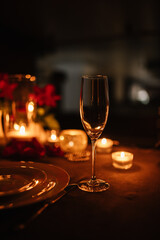 Candlelight date in restaurant. Champagne glasses, bouquet flowers. Romantic dinner setup at night. Table setting for couple, Valentine's Day evening, burning candles for surprise marriage proposal.