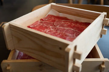 Premium quality sliced beef meat with a perfect fatty texture served on wood box for sukiyaki or shabu.