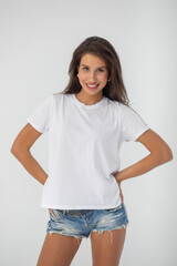 Wall Mural - Beautiful brunette girl in a white T-shirt and denim shorts posing 