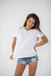 © kanashkin - Beautiful brunette girl in a white T-shirt and denim shorts posing
