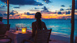 Romantic dinner on sunset. Woman sitting alone on table set with lantern for a romantic meal on beach, yachts and ocean on background. Dinner for a couple in love in luxury outdoor restaurant