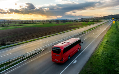 red modern comfortable tourist bus driving through highway at bright sunny sunset. travel and coach 