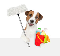 Poster - Cleaning concept. Jack russell terrier puppy holds bucket with washing fluids and mop in paws and looks above empty white banner. isolated on white background